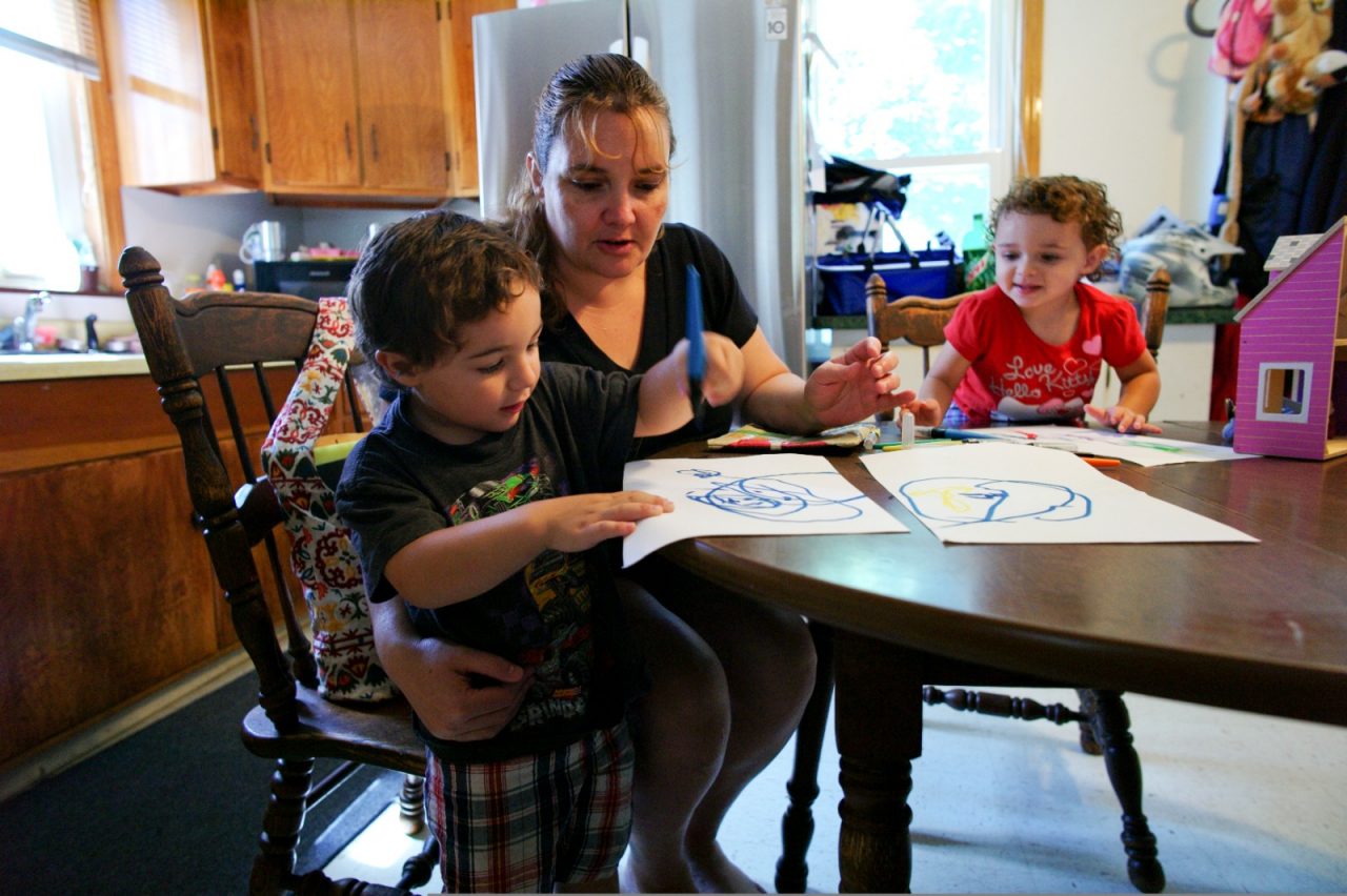 A mother and children enjoy drawing at the kitchen table.