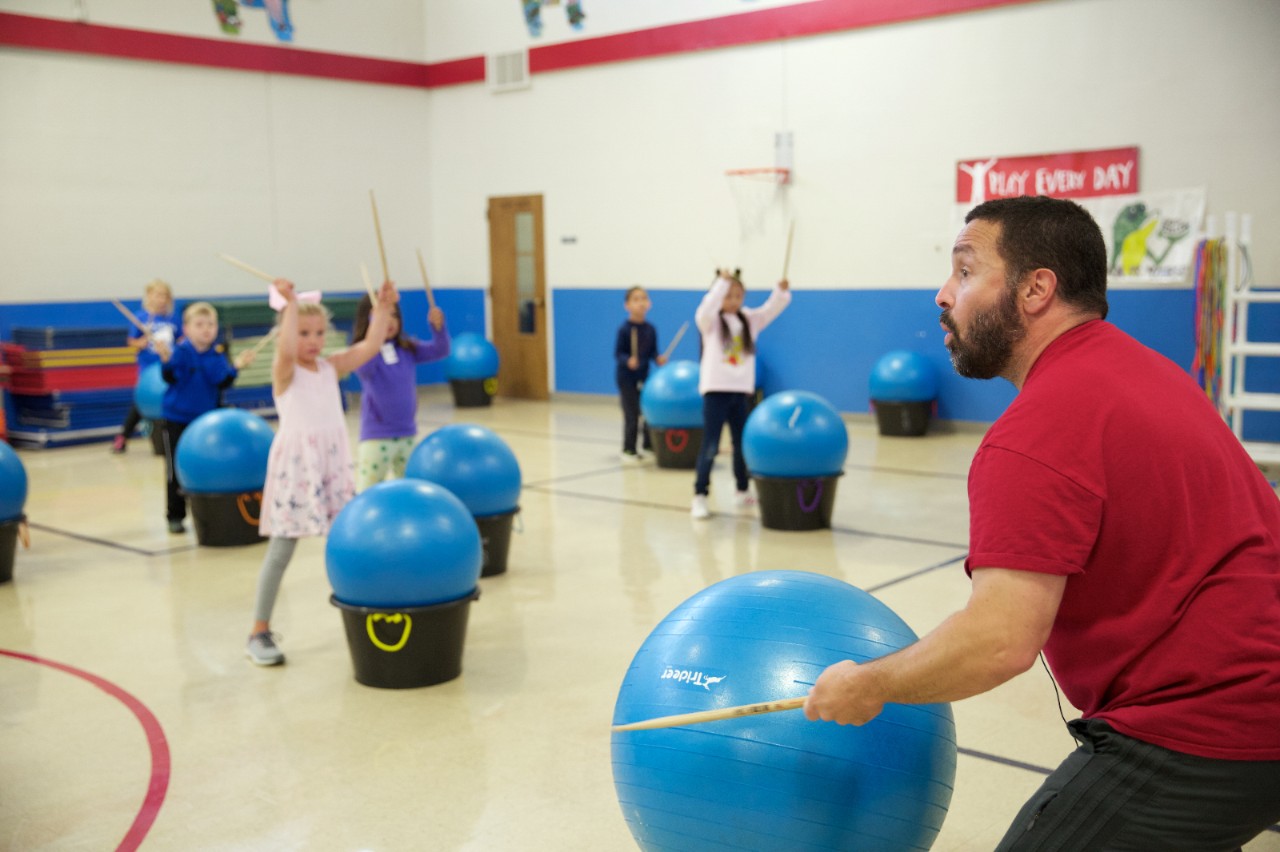A teacher leads an exercise class for young children.