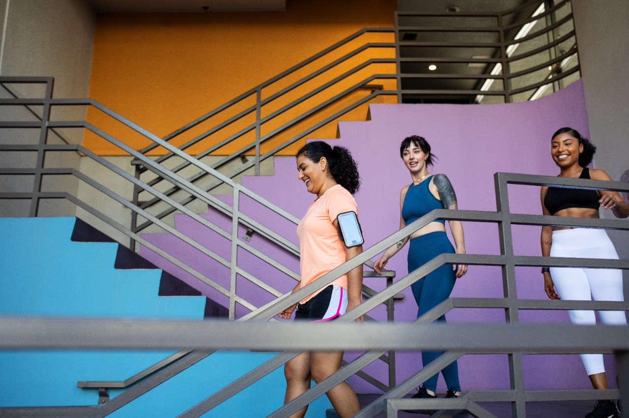 Group of multi-ethnic women walking down the stairs of gym. Three females in sportswear leaving the gym.