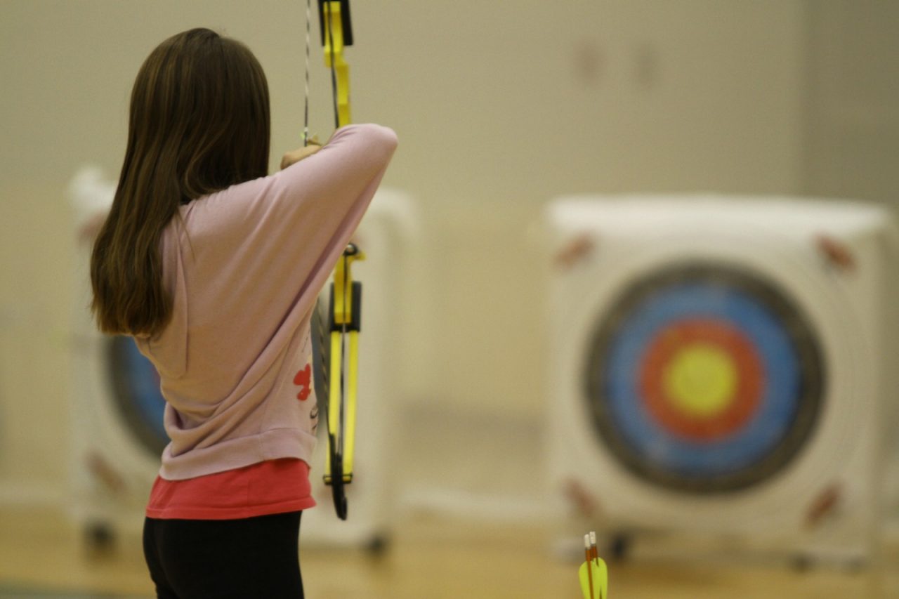 A student shoots an arrow during archery practice. 