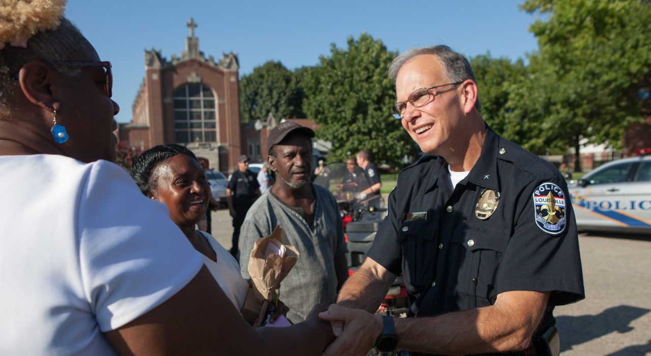 A woman shaking hands and speaking with a police officer during a community gathering.