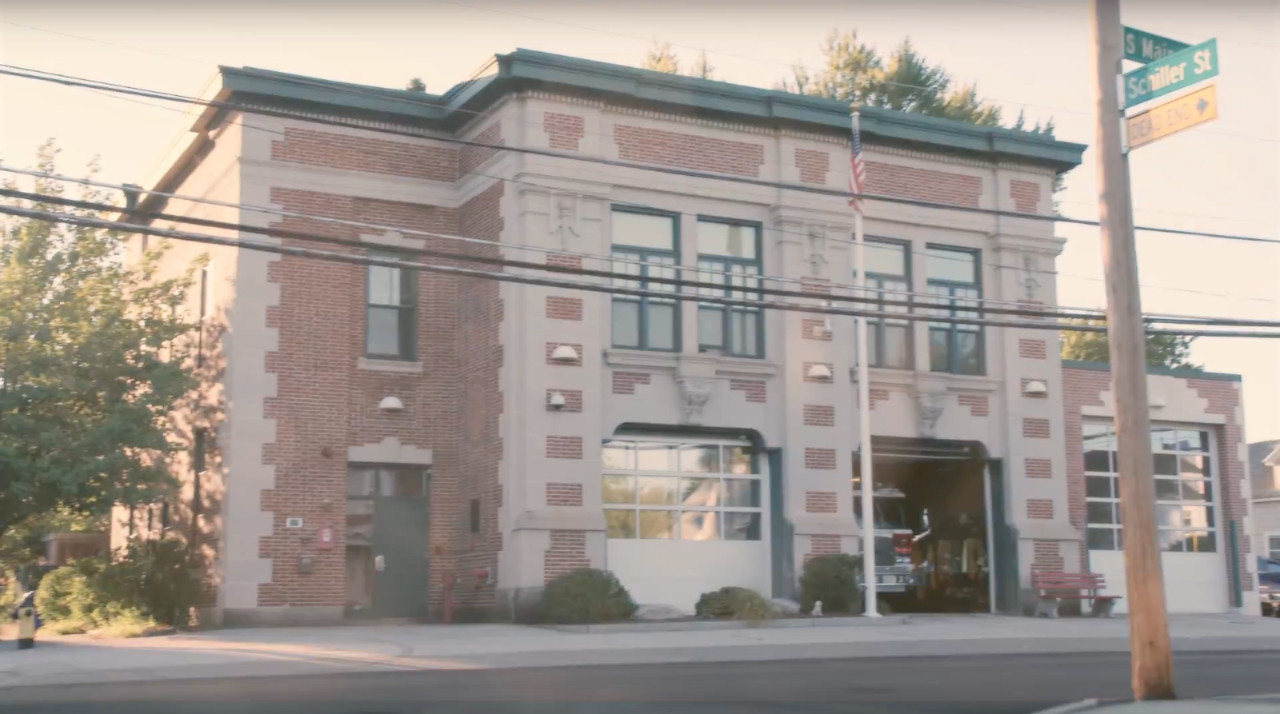 An older, brick firehouse situated at a street corner.