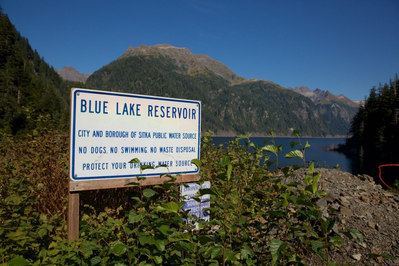 A scenic backdrop behind a sign that reads, "Blue Lake Reservoir."