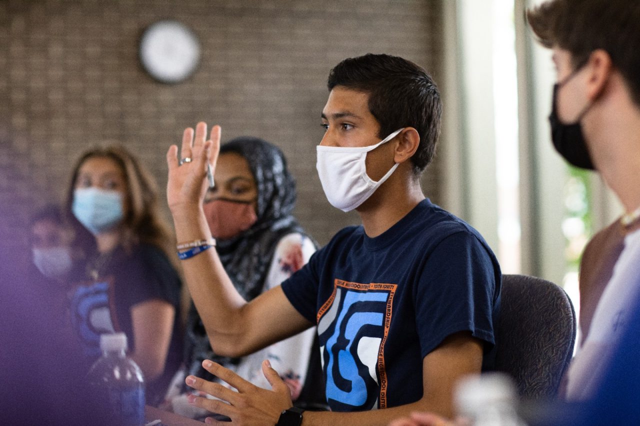 Teenagers, wearing masks, participating in class. 