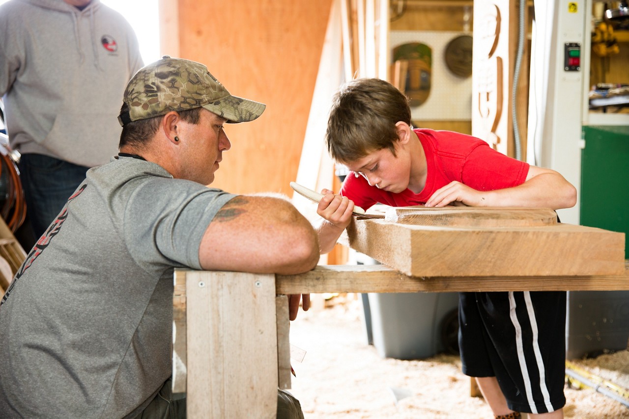 2016 Culture of Health Prize winner. Shoalwater Bay 2016 Culture of Health. Woodcarver Earl Davis teaches his son Aiden the traditional techniques.