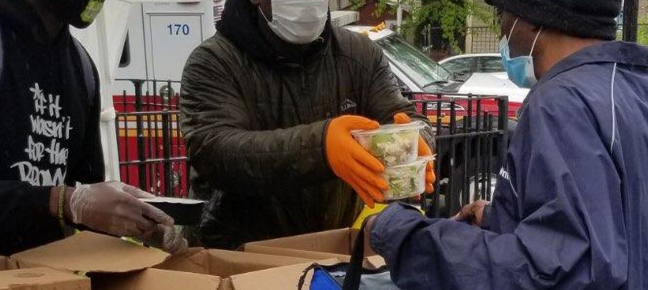 Men wearing protective masks distribute food.