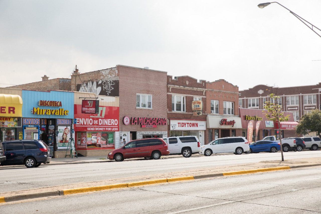 Small stores and cars lining a town's main street.